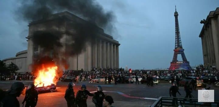 A burning vehicle illuminates a Paris street during overnight unrest.